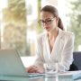 Professional businesswoman working on laptop in modern office with natural lighting