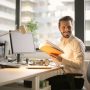 Professional business executive reading in modern office environment with dual monitors